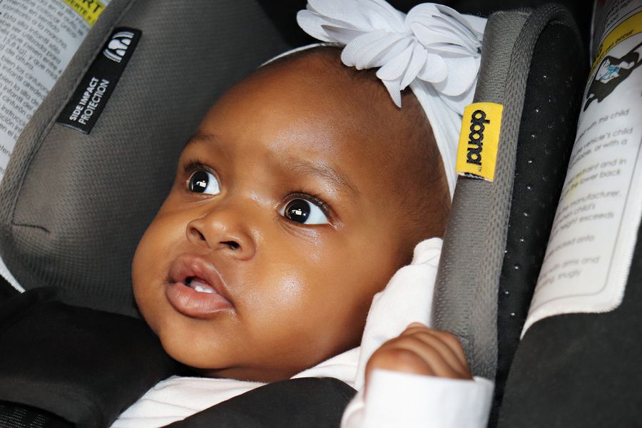 baby buckled snugly in a car seat wearing thin winter layers for safe travel