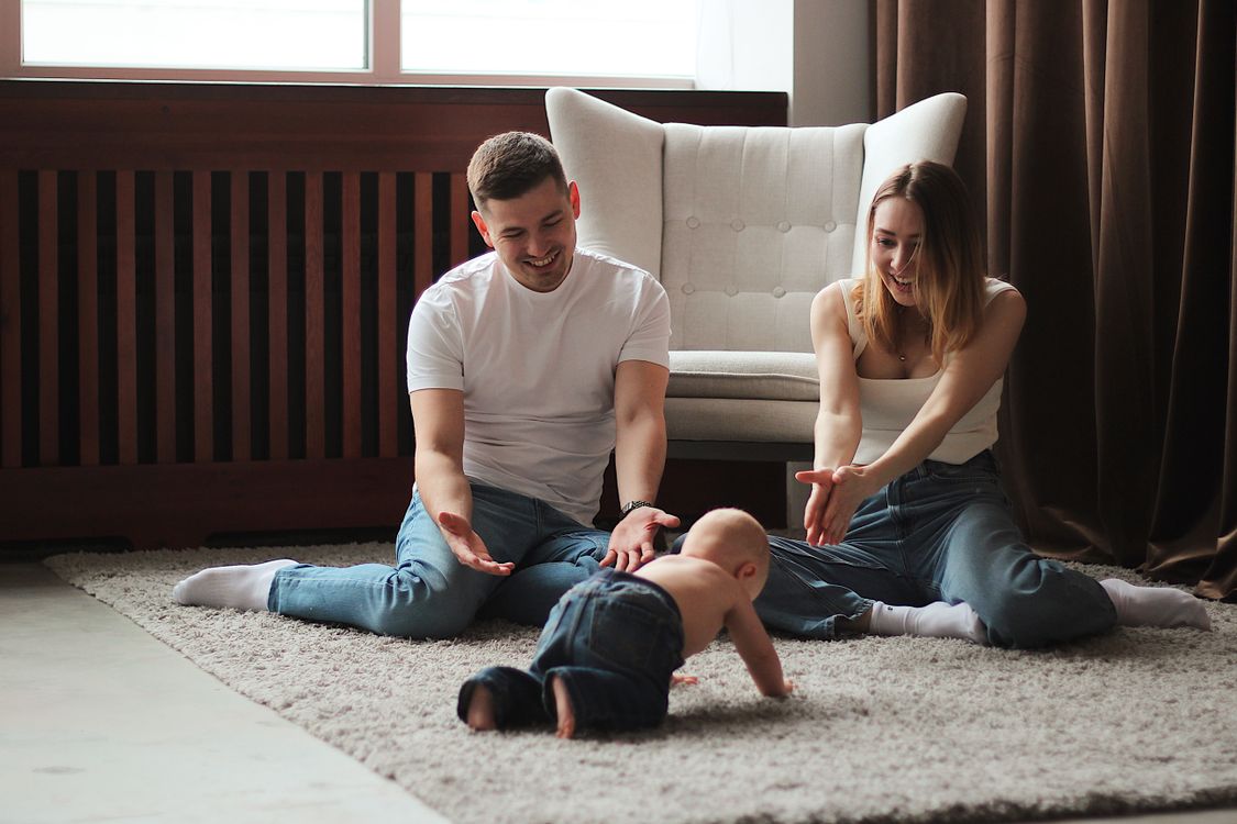 parents playing with their baby on the floor indoors during winter playtime