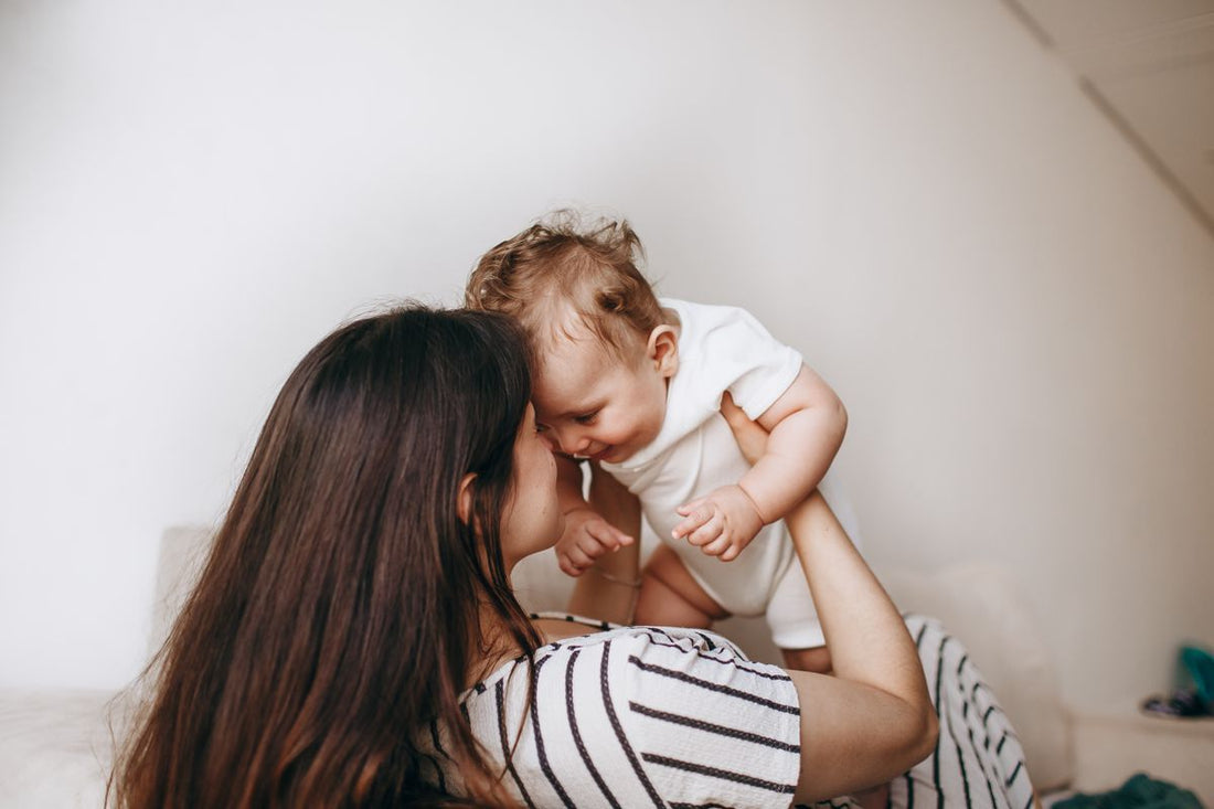 mother encouraging her baby during tummy time on a soft play mat at home