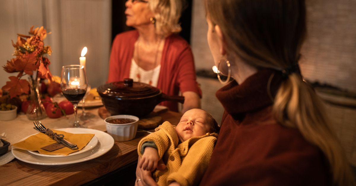 family gathered around the Thanksgiving dinner table during baby's first Thanksgiving celebration