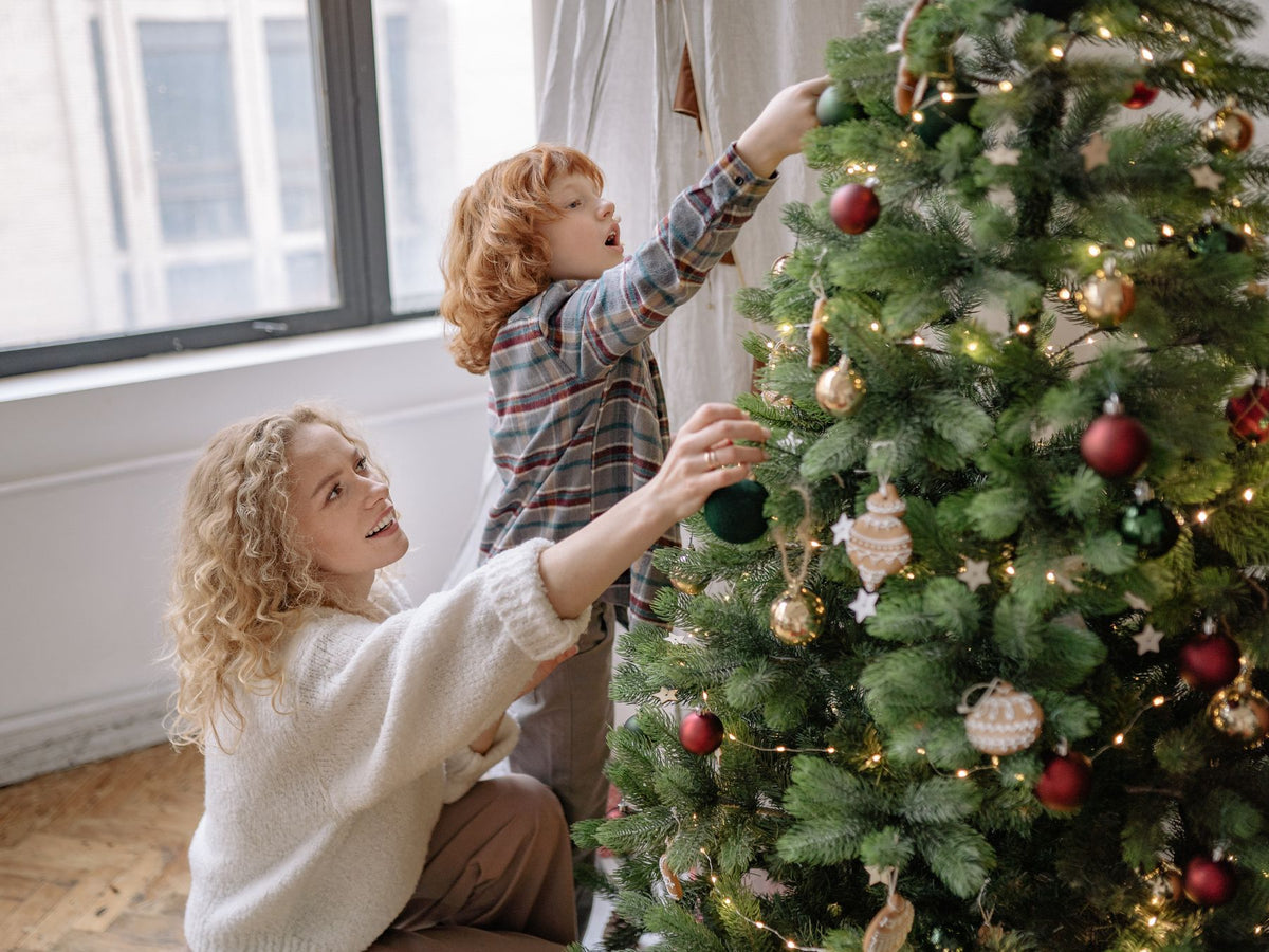 mother and young child decorating a christmas tree with ornaments for a baby-safe holiday