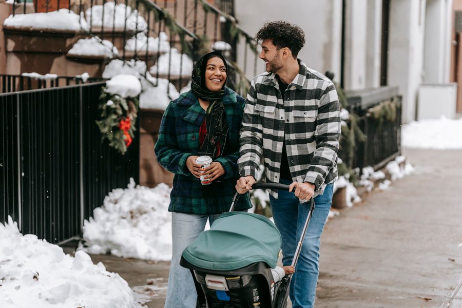 family walking with a baby in a stroller on a snowy winter day