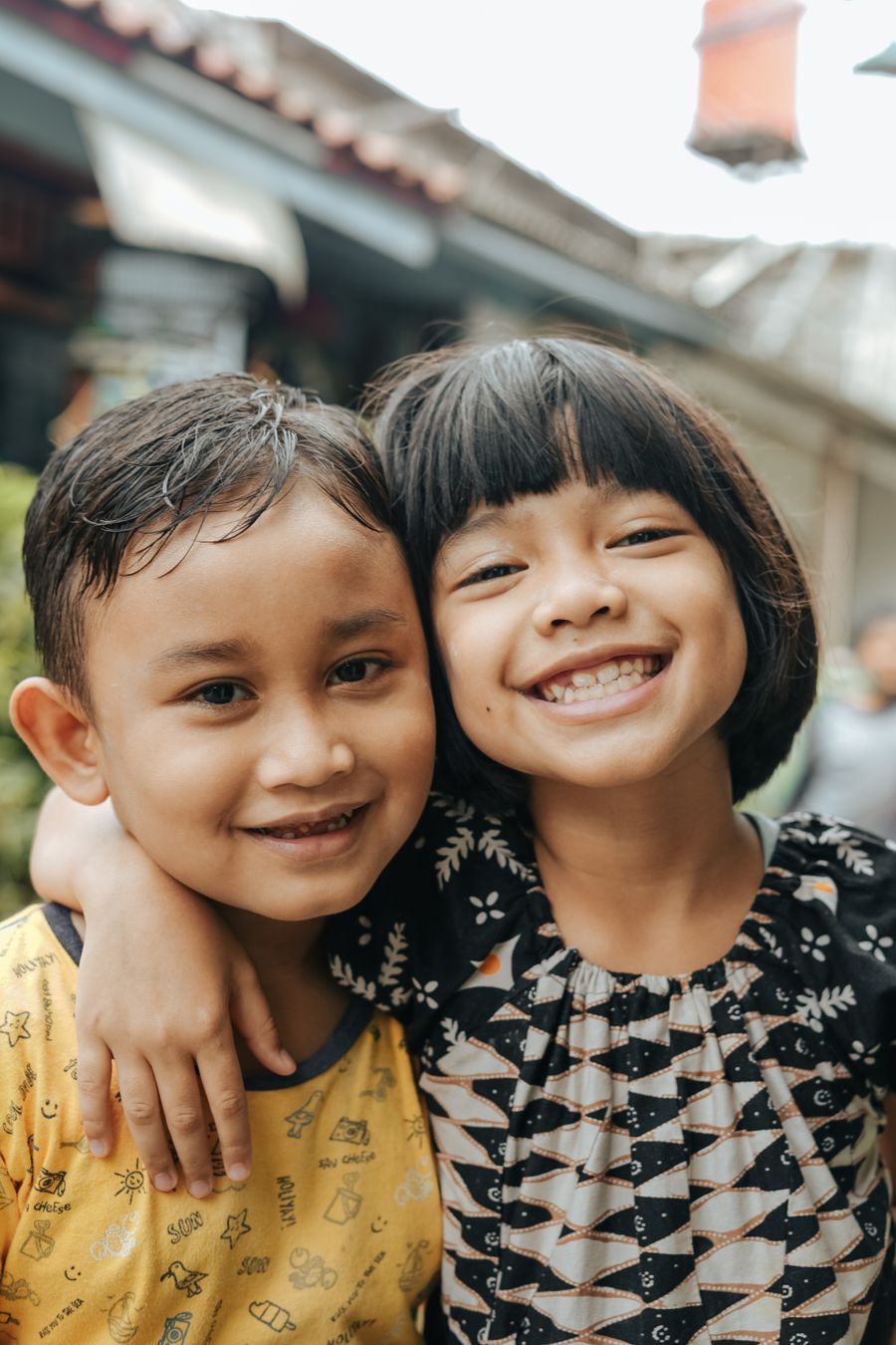 two young siblings smiling and hugging each other while spending happy time at home