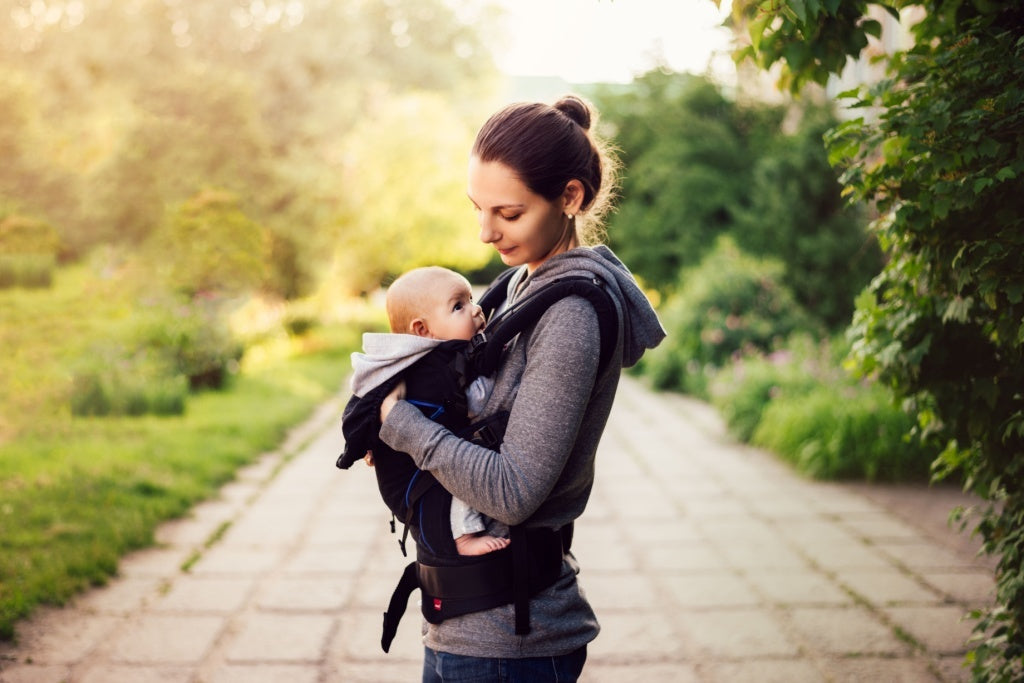 Mother walking outdoors with her baby on a holiday outing with a packed diaper bag